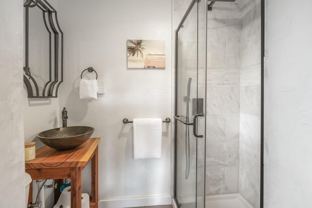 bathroom with a shower with shower door and sink