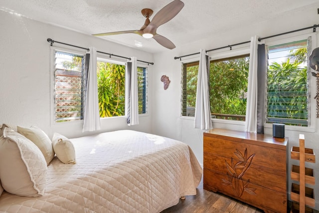 bedroom with ceiling fan, wood-type flooring, and a textured ceiling