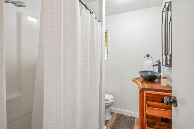 bathroom with hardwood / wood-style floors, a shower with curtain, sink, toilet, and a textured ceiling