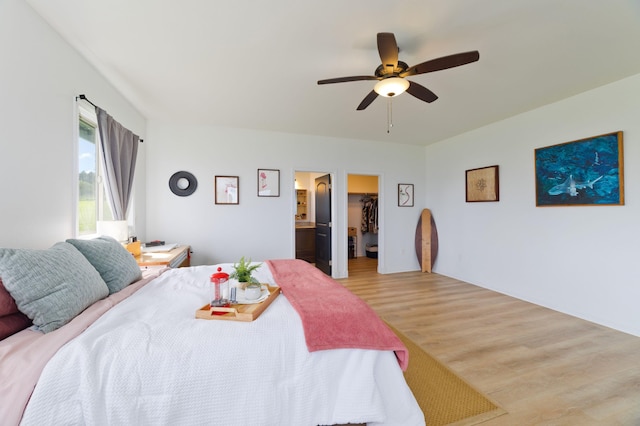 bedroom with ceiling fan, ensuite bathroom, a walk in closet, a closet, and hardwood / wood-style flooring