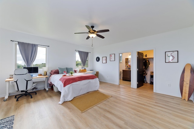 bedroom with light hardwood / wood-style flooring, ceiling fan, a spacious closet, connected bathroom, and a closet