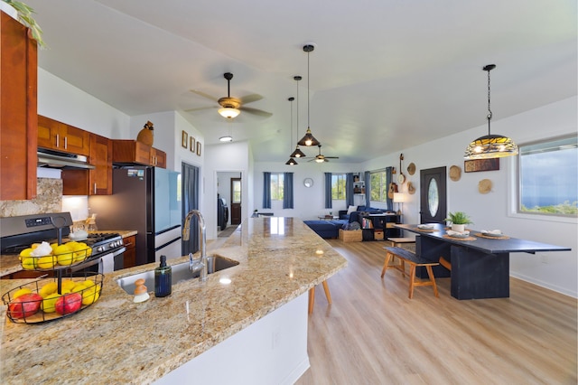 kitchen with stainless steel gas range oven, sink, ceiling fan, light stone countertops, and tasteful backsplash