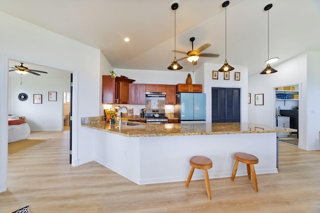 kitchen featuring kitchen peninsula, appliances with stainless steel finishes, sink, decorative light fixtures, and lofted ceiling