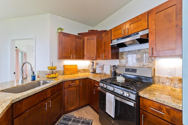 kitchen with backsplash, stainless steel range with gas cooktop, sink, light stone countertops, and kitchen peninsula