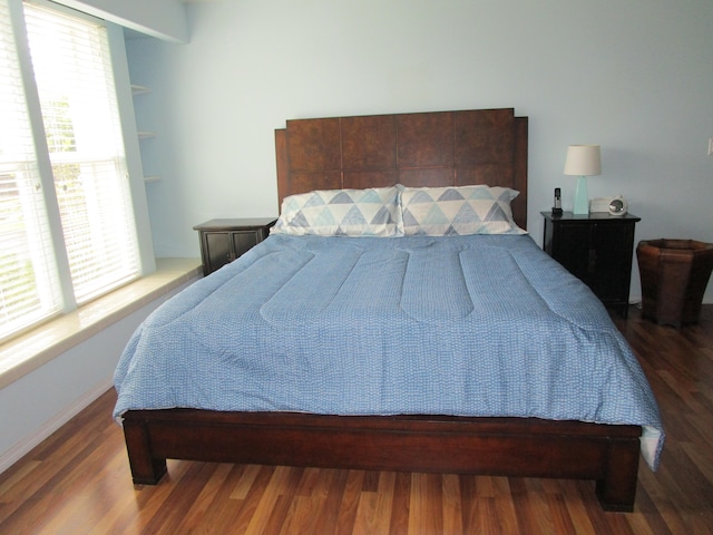 bedroom with dark hardwood / wood-style flooring and multiple windows