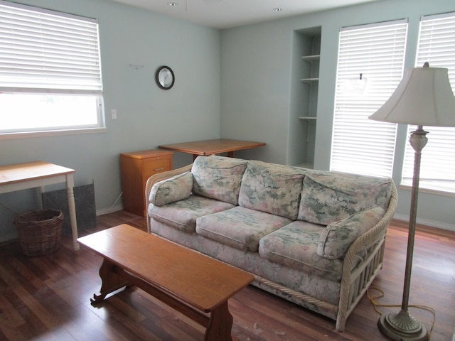 living room featuring built in shelves, dark hardwood / wood-style flooring, and a wealth of natural light