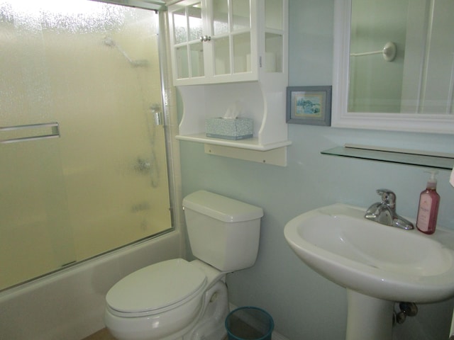 full bathroom featuring toilet, combined bath / shower with glass door, and sink