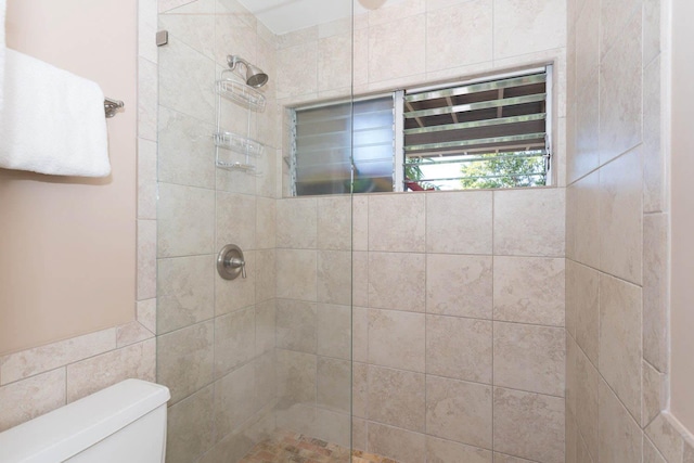 bathroom featuring a tile shower and toilet