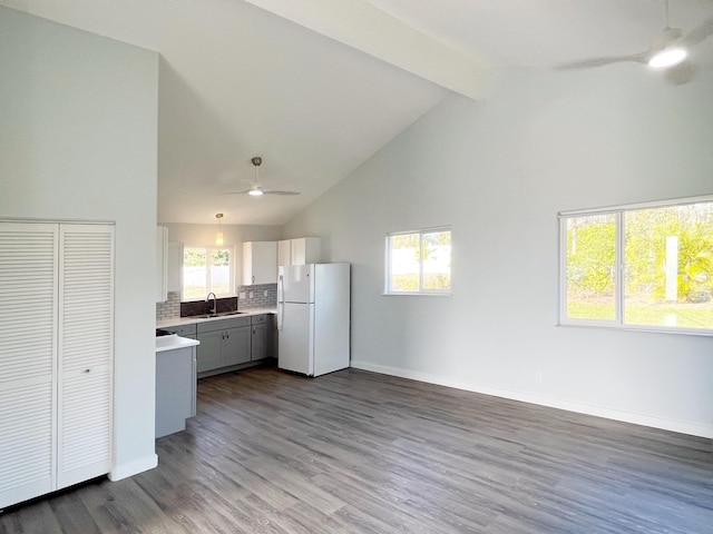 kitchen with white fridge, hardwood / wood-style floors, decorative backsplash, high vaulted ceiling, and sink