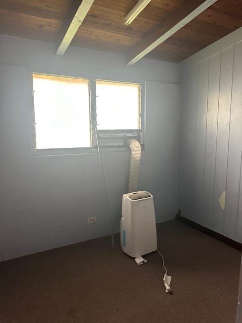 unfurnished room featuring wood ceiling, plenty of natural light, dark carpet, and beamed ceiling