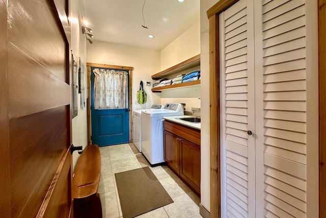 laundry area with light tile patterned floors, cabinets, washer and clothes dryer, and sink