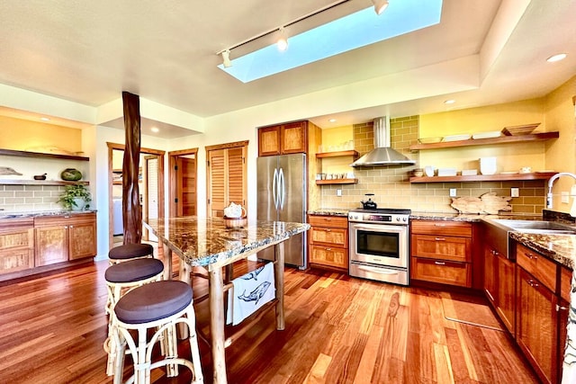 kitchen featuring wall chimney exhaust hood, stainless steel appliances, light hardwood / wood-style floors, sink, and backsplash