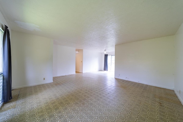 empty room with ceiling fan and a textured ceiling