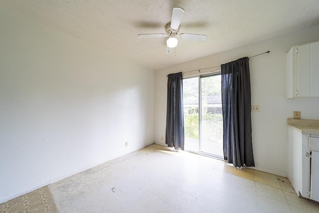 empty room with ceiling fan and a textured ceiling