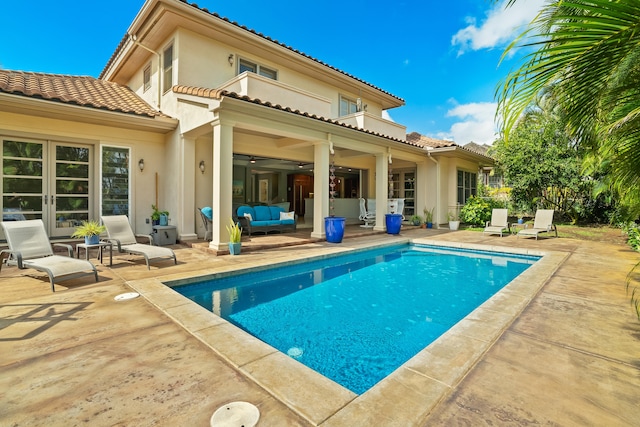 rear view of property featuring a patio area, ceiling fan, a balcony, and outdoor lounge area