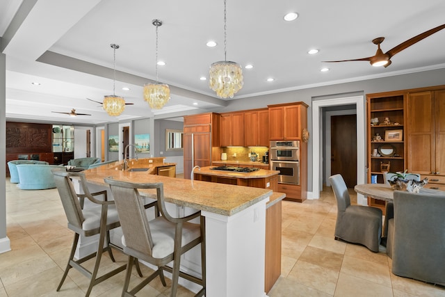 kitchen with ceiling fan with notable chandelier, stainless steel appliances, sink, a large island with sink, and decorative light fixtures