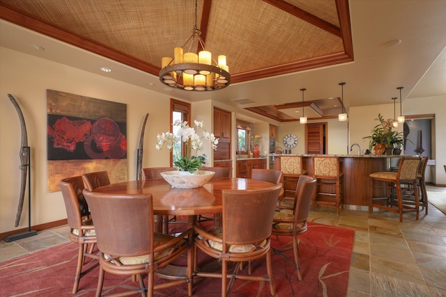 dining room featuring a raised ceiling, ornamental molding, and an inviting chandelier