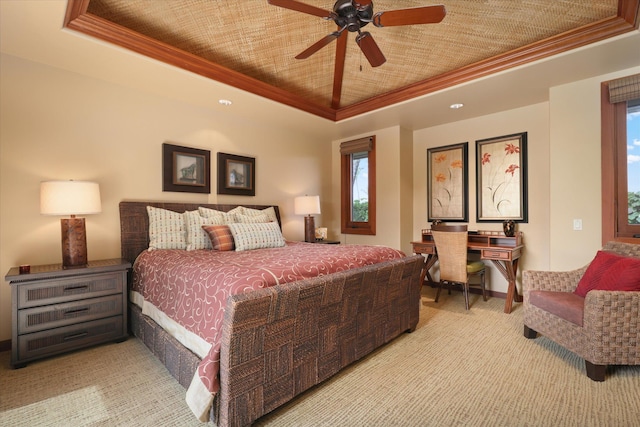 carpeted bedroom with a tray ceiling, ornamental molding, and ceiling fan