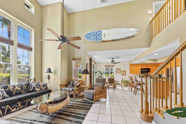 living room with a high ceiling, light tile patterned floors, and ceiling fan