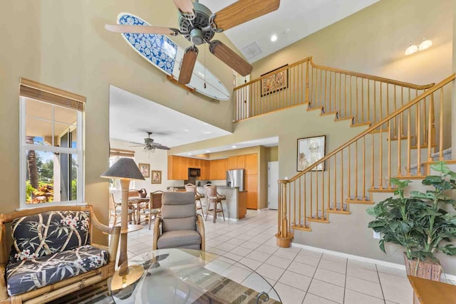 tiled living room featuring ceiling fan and a high ceiling