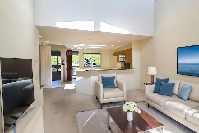 living room with a towering ceiling and light colored carpet