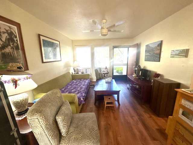 living room featuring ceiling fan, dark wood-type flooring, and a textured ceiling