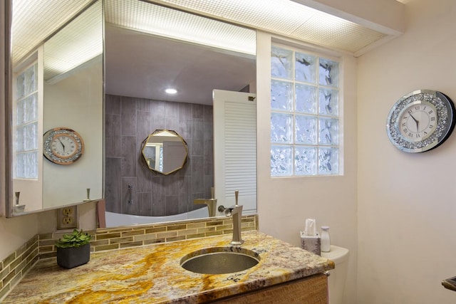 bathroom featuring backsplash, vanity, and toilet