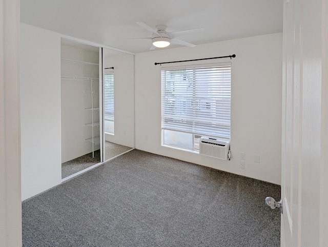 unfurnished bedroom featuring ceiling fan, a closet, dark carpet, and cooling unit