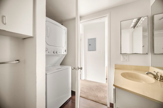 washroom featuring stacked washing maching and dryer, sink, and electric panel