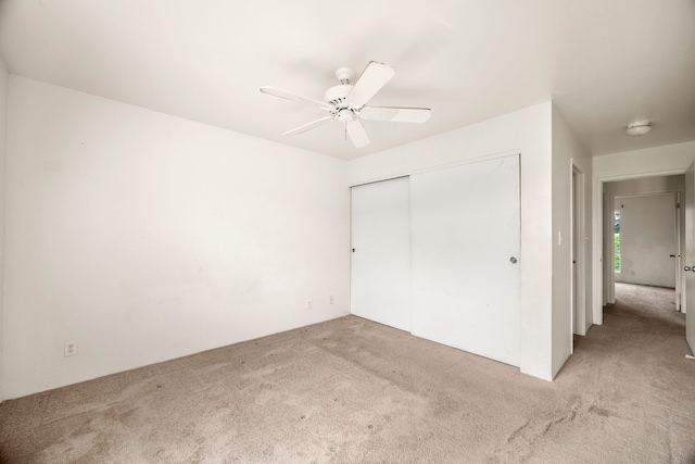 unfurnished bedroom featuring light carpet, a closet, and ceiling fan