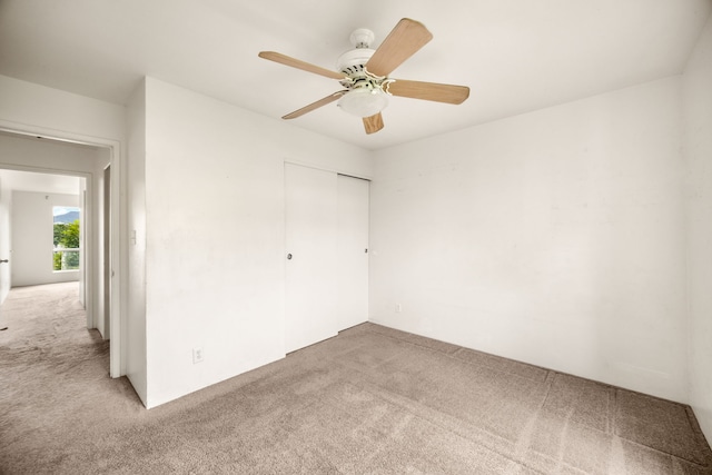 unfurnished bedroom featuring light colored carpet, a closet, and ceiling fan