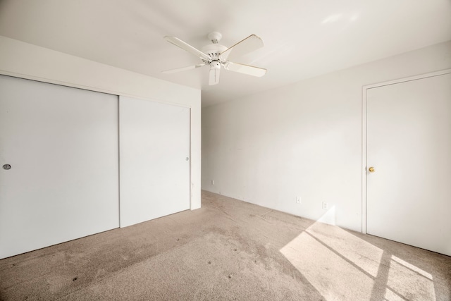 unfurnished bedroom with ceiling fan, a closet, and light carpet