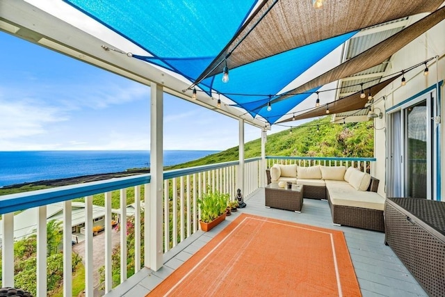 balcony with an outdoor living space and a water view