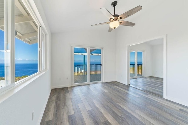 unfurnished room featuring ceiling fan, a water view, light wood-type flooring, and vaulted ceiling