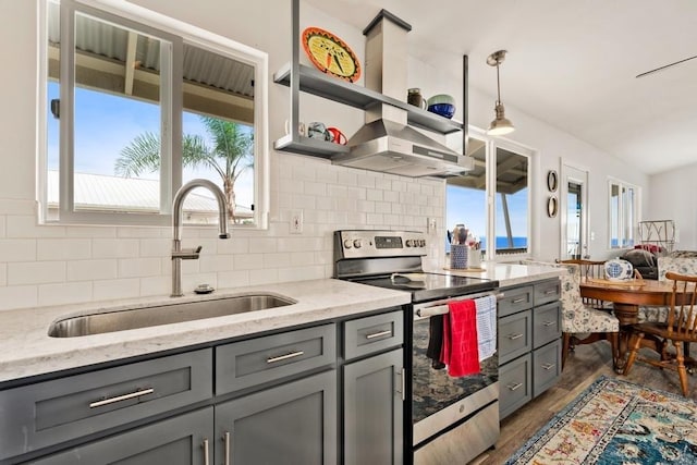 kitchen featuring light stone countertops, sink, dark hardwood / wood-style floors, pendant lighting, and electric stove