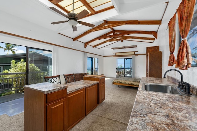 kitchen with light carpet, ceiling fan, sink, vaulted ceiling with beams, and a center island