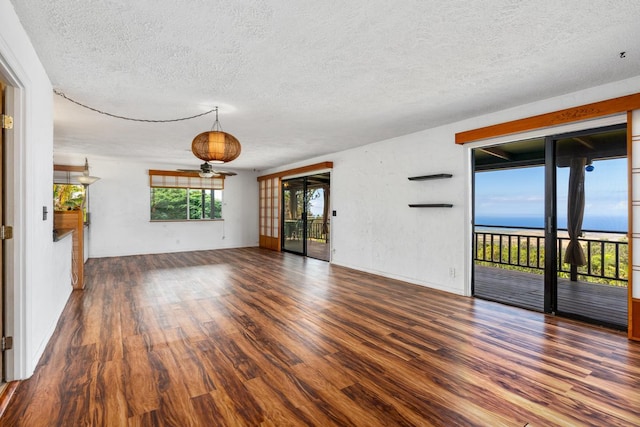 unfurnished living room featuring a textured ceiling, dark hardwood / wood-style floors, and a water view