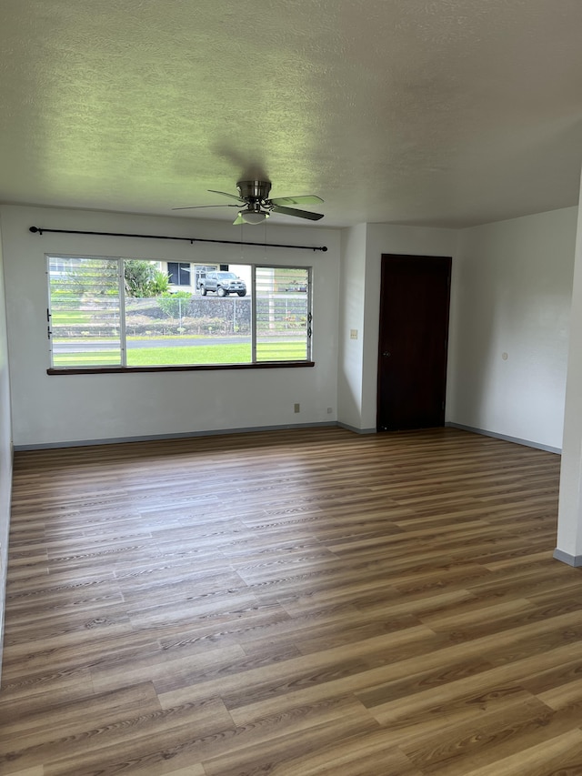 empty room with ceiling fan, a textured ceiling, and hardwood / wood-style flooring