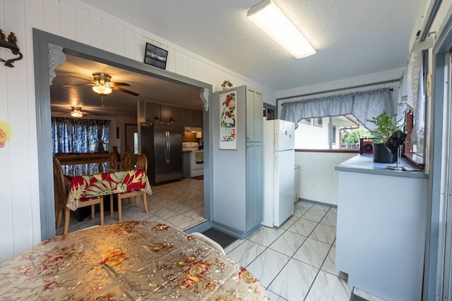 kitchen featuring ceiling fan, wooden walls, and white appliances