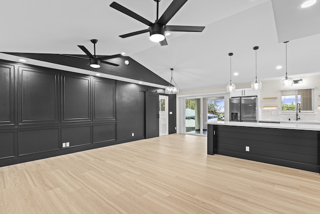 kitchen featuring lofted ceiling, stainless steel fridge, a healthy amount of sunlight, and decorative light fixtures