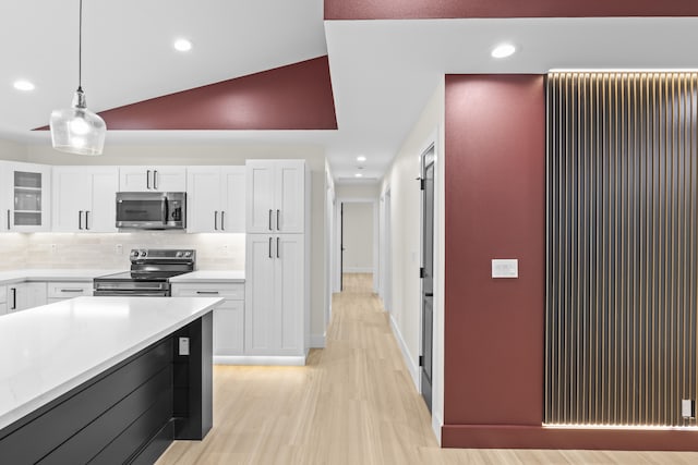 kitchen with stainless steel appliances, tasteful backsplash, pendant lighting, white cabinets, and light wood-type flooring