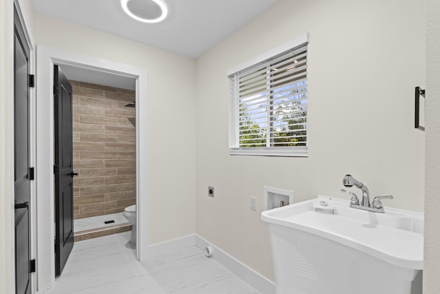 bathroom with tiled shower, sink, and toilet