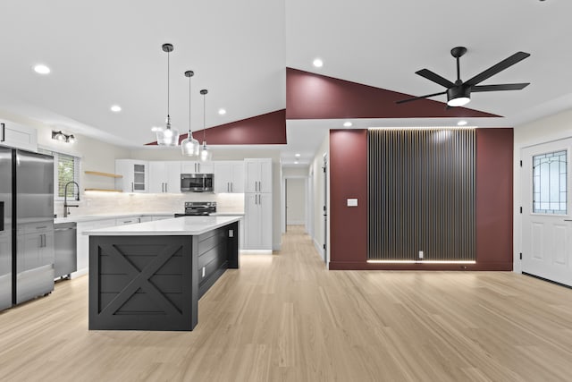 kitchen with a center island, backsplash, appliances with stainless steel finishes, decorative light fixtures, and white cabinetry