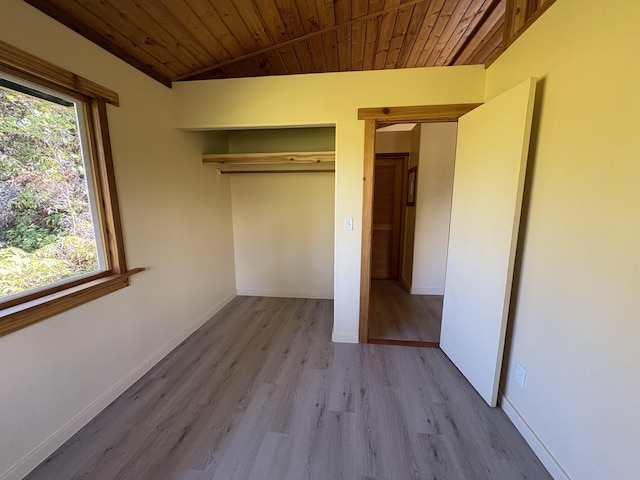 unfurnished bedroom featuring wood ceiling, vaulted ceiling, light hardwood / wood-style floors, and a closet