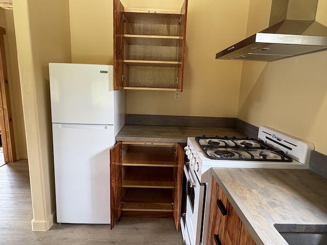 kitchen with white appliances, wall chimney exhaust hood, and light hardwood / wood-style flooring