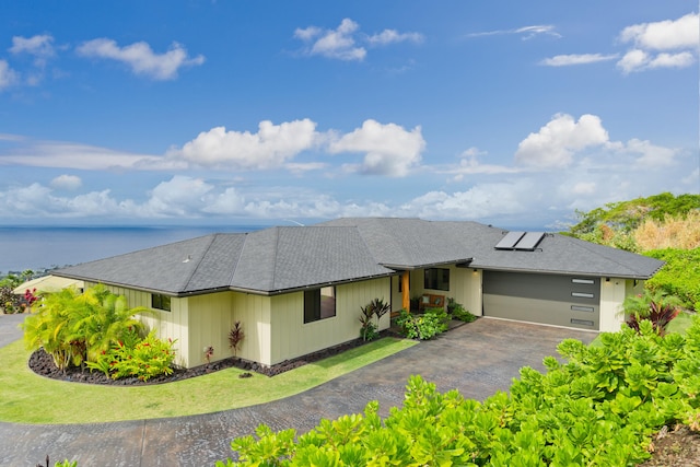 view of front of property with a garage, solar panels, and a water view