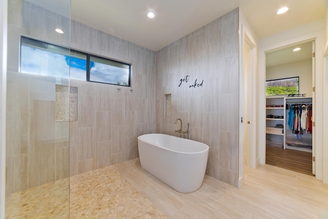 bathroom with separate shower and tub and tile walls