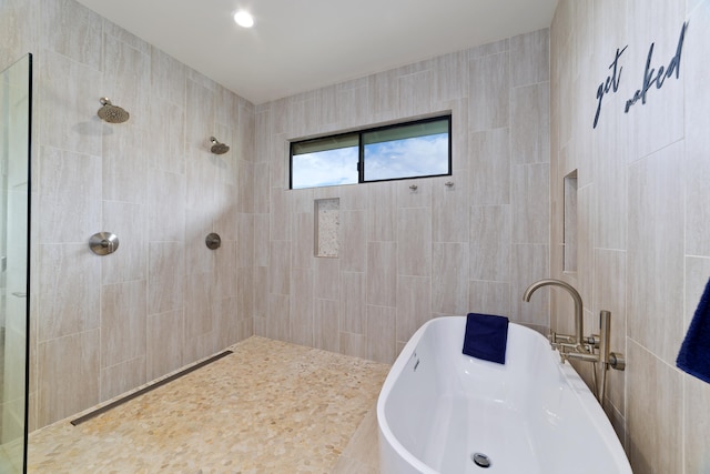 bathroom featuring plus walk in shower and tile walls