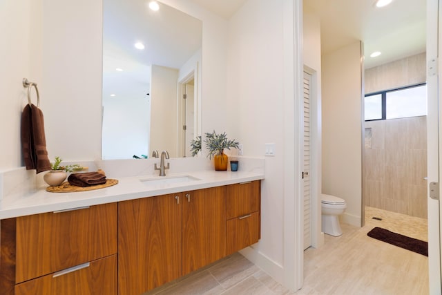 bathroom featuring vanity, toilet, and tiled shower