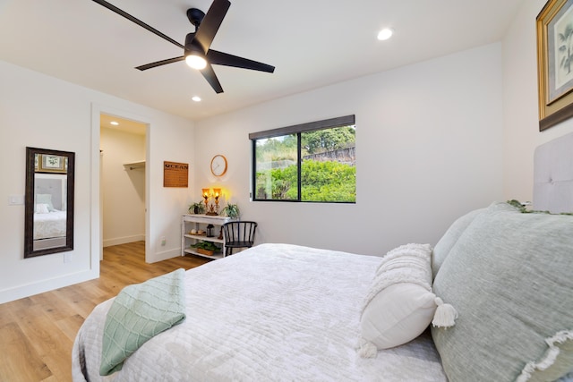 bedroom featuring a walk in closet, ceiling fan, and light wood-type flooring